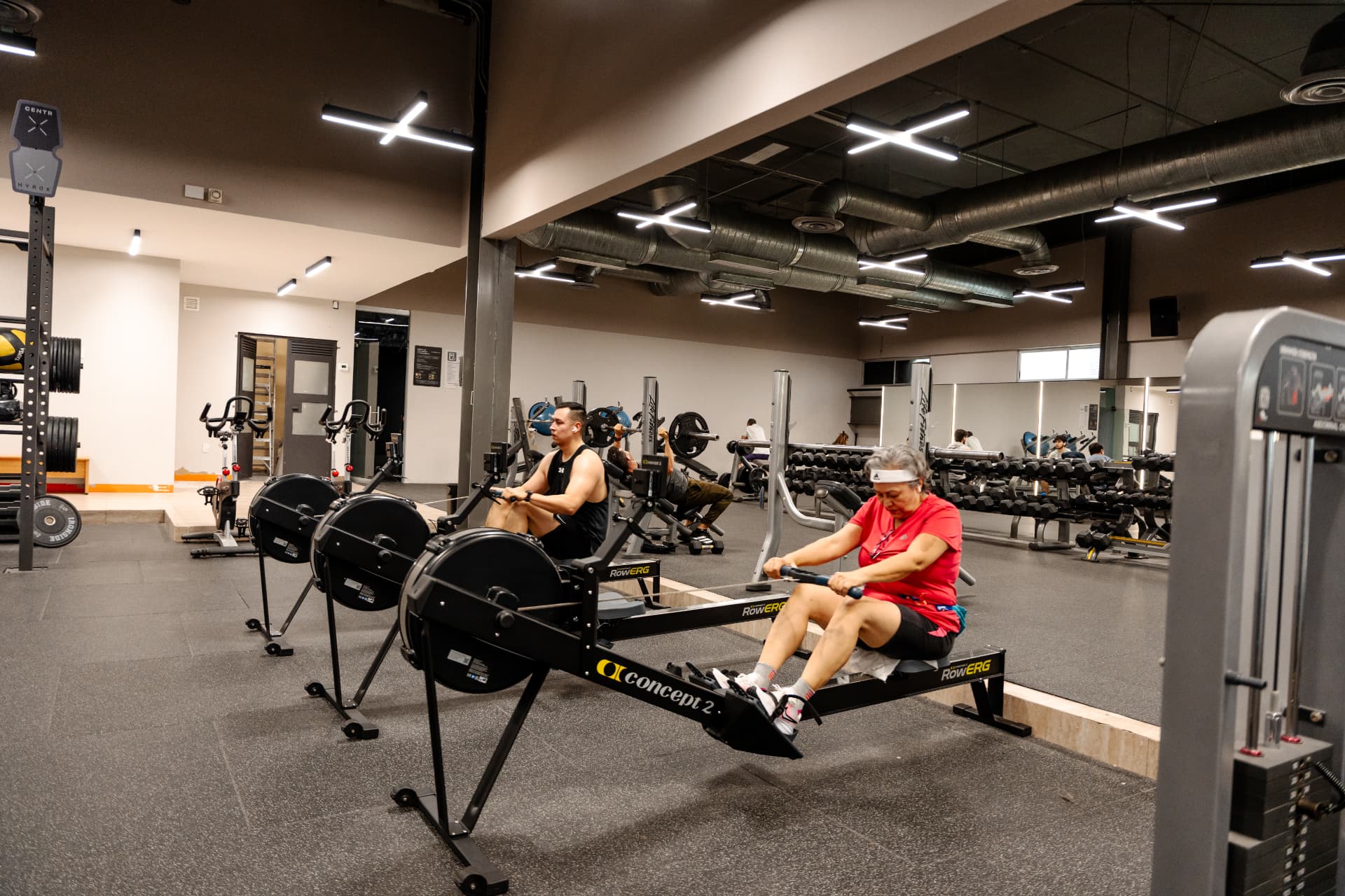 Dos personas entrenando en remadoras dentro del centro