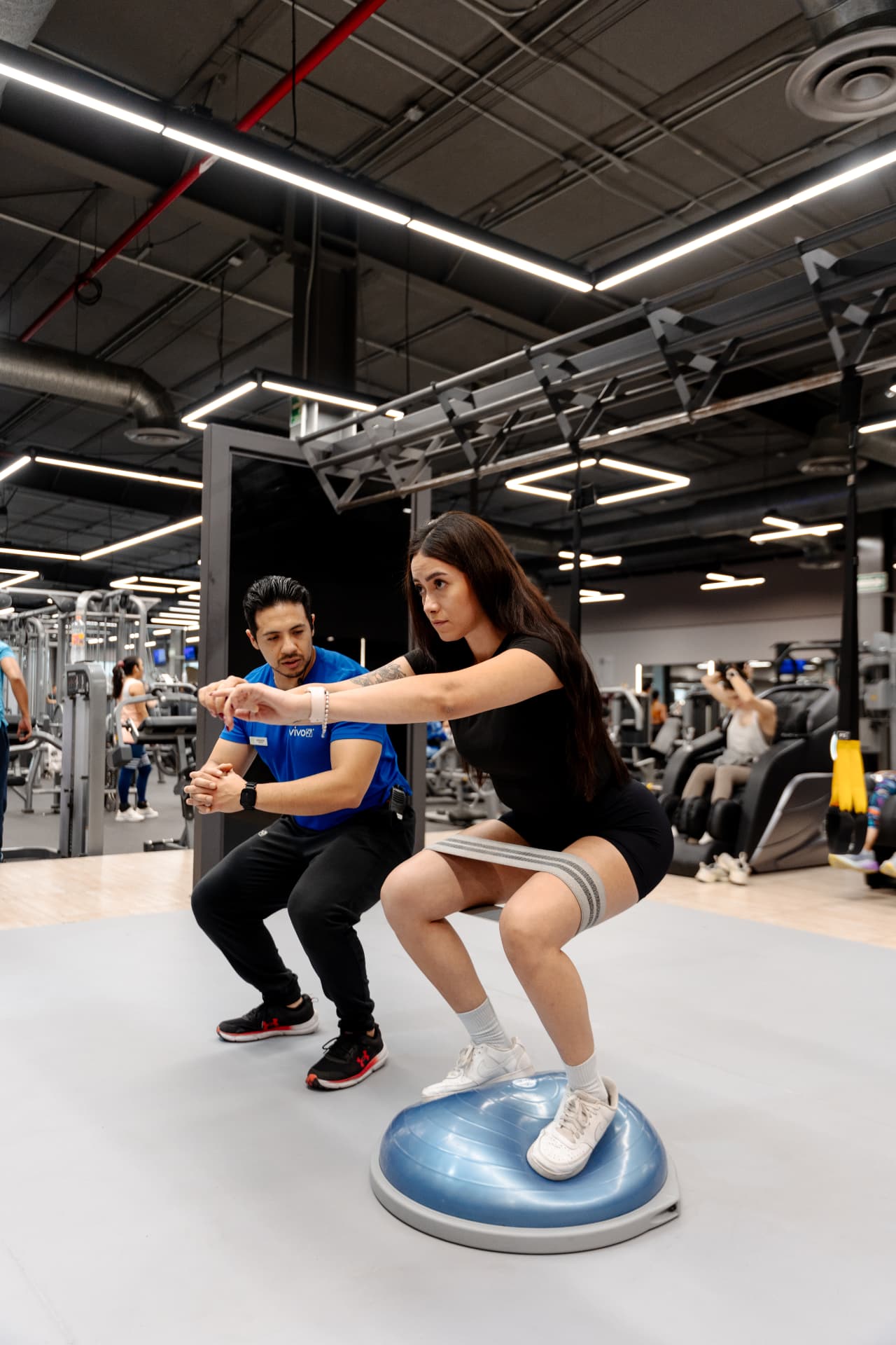 Entrenadora acompañando a una persona durante una sentadilla asistida